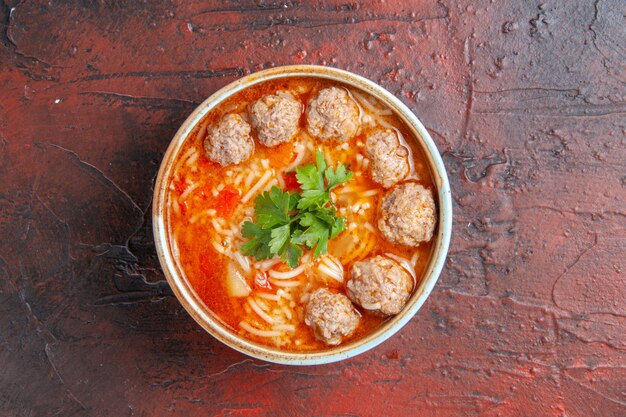 Vista dall'alto della zuppa di polpette con noodles in una ciotola marrone su sfondo scuro