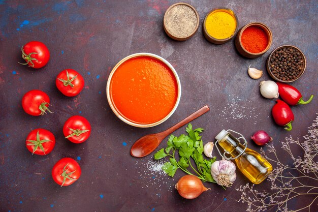 Vista dall'alto della zuppa di pomodoro cucinata con pomodori freschi con condimenti sul tavolo nero