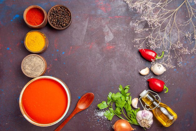 Vista dall'alto della zuppa di pomodoro cucinata con pomodori freschi con diversi condimenti su nero