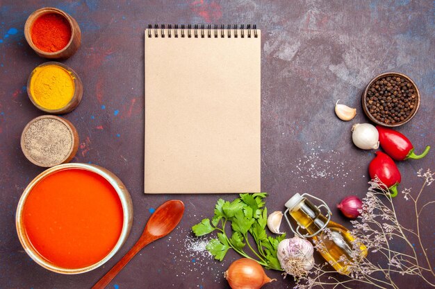 Vista dall'alto della zuppa di pomodoro cucinata con pomodori freschi con diversi condimenti su nero