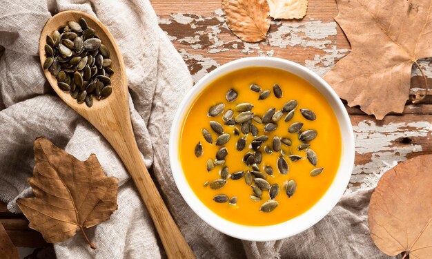 Vista dall'alto della zuppa di zucca autunnale con semi e foglie