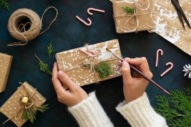 Vista dall'alto delle mani che decorano il regalo di Natale con la vernice