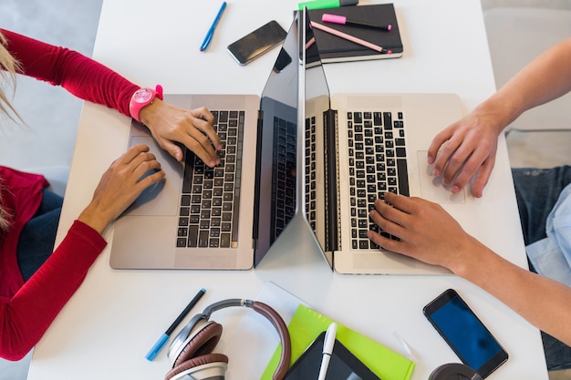 Vista dall'alto delle mani di giovane uomo e donna che lavorano al computer portatile in ufficio di co-working, digitando sulla tastiera