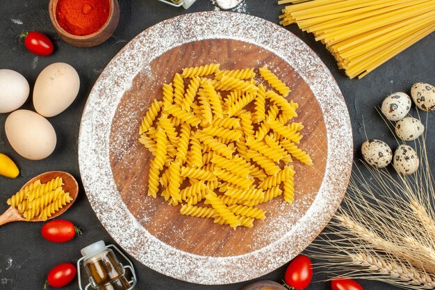 Vista dall'alto delle uova di pasta cruda picchi di bottiglia di olio caduta su sfondo nero