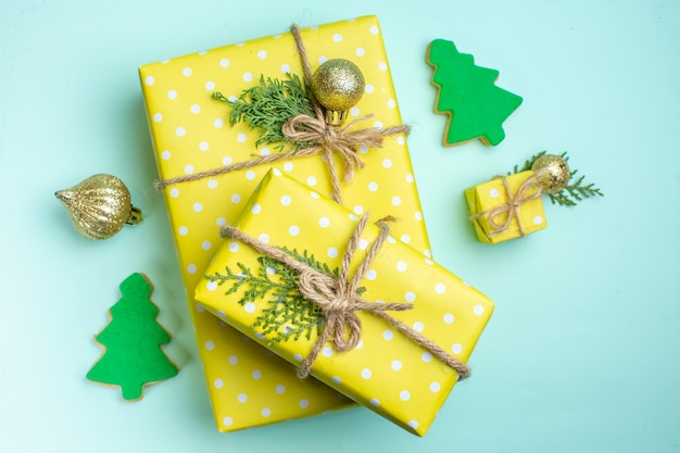 Vista dall'alto dello sfondo natalizio con scatole regalo gialle di diverse dimensioni e accessori decorativi su sfondo verde pastello
