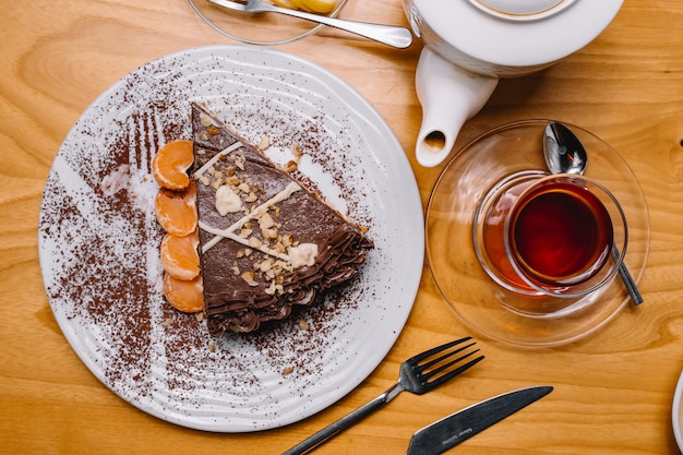 Vista dall'alto dessert torta al cioccolato con fette di mandarino e un bicchiere di tè