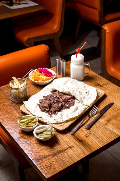 Vista dall'alto di agnello doner kebab servito in focaccia con patatine sottaceto e ayran