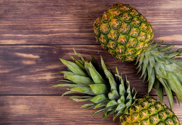 Vista dall'alto di ananas sul lato destro e sfondo in legno con spazio di copia