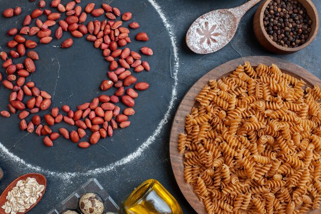 Vista dall'alto di arachidi rosse fresche con condimenti di pasta cruda e uova su pasta di latte all'uovo di spuntino di pasto alimentare di colore scuro da tavola