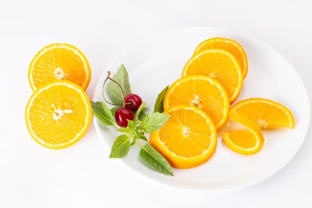 Vista dall'alto di arance fresche a fette all'interno del piatto bianco sul succo di colore della frutta sfondo bianco