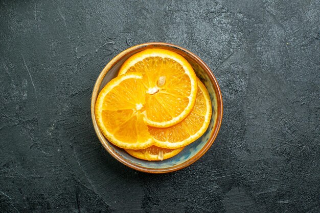 Vista dall'alto di arance fresche affettate all'interno del piatto su succo di frutta tropicale esotica di agrumi di superficie scura