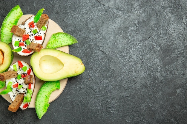 Vista dall'alto di avocado cremosi con pane e pepe e avocado freschi sulla superficie grigia