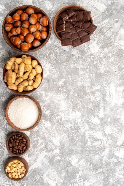 Vista dall'alto di barrette di cioccolato con nocciole e arachidi sulla superficie bianca