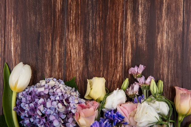 Vista dall'alto di bellissimi fiori come le rose tulipano gardenzia isolate su uno sfondo di legno con spazio di copia