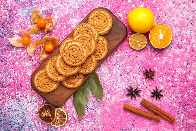 Vista dall'alto di biscotti dolci rotondi rivestiti con cannella e limone sulla superficie rosa