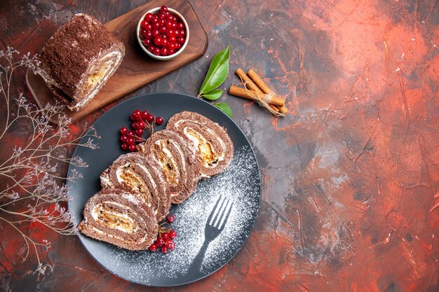 Vista dall'alto di biscotti rotoli fette con frutta sulla superficie scura