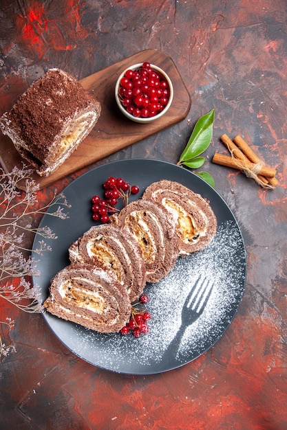 Vista dall'alto di biscotti rotoli fette con frutta sulla superficie scura