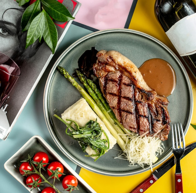 Vista dall'alto di bistecca di manzo servita con asparagi bolliti, spinaci e salsa