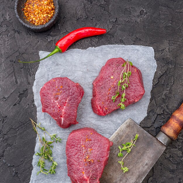 Vista dall'alto di carne con erbe e mannaia