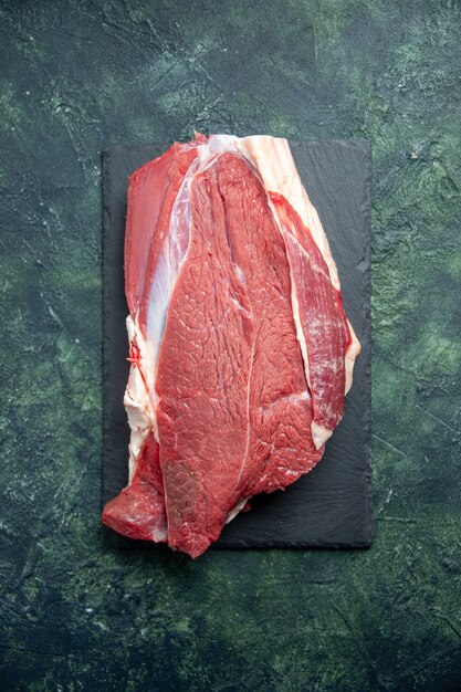 Vista dall'alto di carne rossa fresca cruda sul tagliere su sfondo di colori verdi misti neri