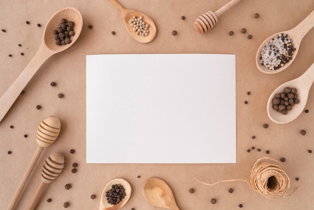 Vista dall'alto di carta vuota con cucchiai di legno e condimenti