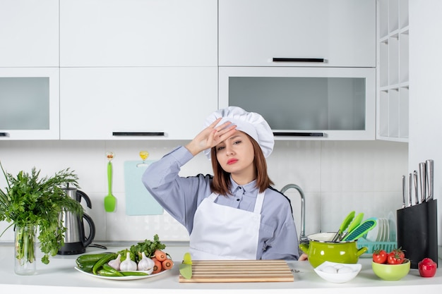 Vista dall'alto di chef donna e verdure fresche che soffrono di mal di testa nella cucina bianca