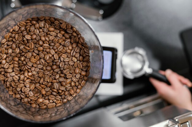 Vista dall'alto di chicchi di caffè tostati e barista femminile che prepara il caffè