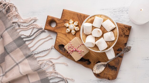 Vista dall'alto di cioccolata calda e marshmallow in tazza con cucchiaio e coperta