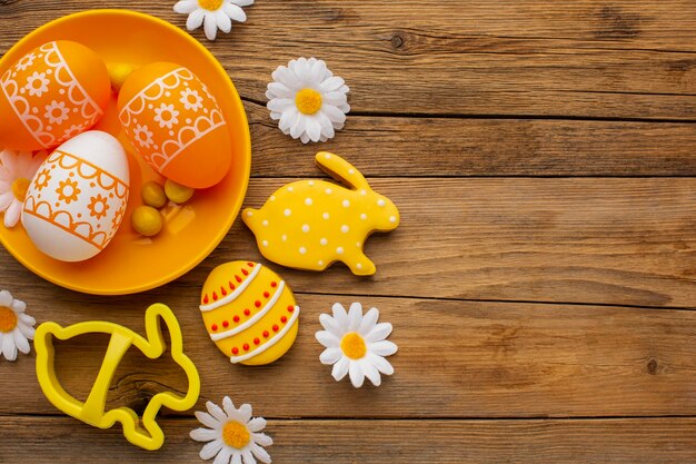 Vista dall'alto di colorate uova di Pasqua sulla piastra con fiori di camomilla e copia spazio