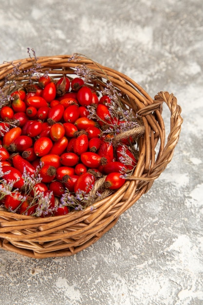 Vista dall'alto di cornioli freschi aspri all'interno del cestello sulla superficie bianco-chiaro frutti berry vitamina acido mellow pianta albero