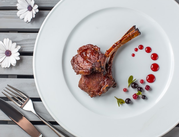 vista dall'alto di costolette di agnello bistecca sul piatto bianco con decorazione punti di syrop