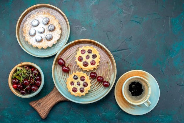 Vista dall'alto di cupcakes con ciliegie accanto all'americano sul blu,