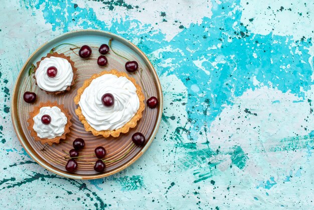 Vista dall'alto di cupcakes con ciliegie fresche e crema gustosa