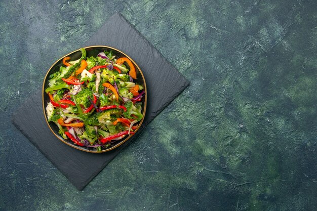 Vista dall'alto di deliziosa insalata di verdure con vari ingredienti su tagliere nero