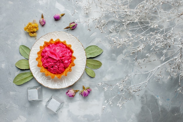 Vista dall'alto di deliziosa piccola torta con crema rosa e cioccolatini su luce, torta dolce crema tè cuocere