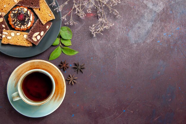 Vista dall'alto di deliziose fette di torta con una tazza di tè sul nero