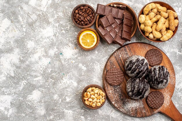 Vista dall'alto di deliziose torte al cioccolato con biscotti e arachidi sulla superficie bianca