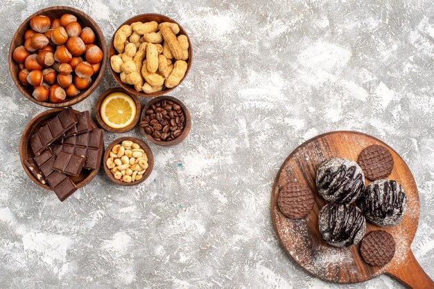 Vista dall'alto di deliziose torte al cioccolato con biscotti e arachidi sulla superficie bianca