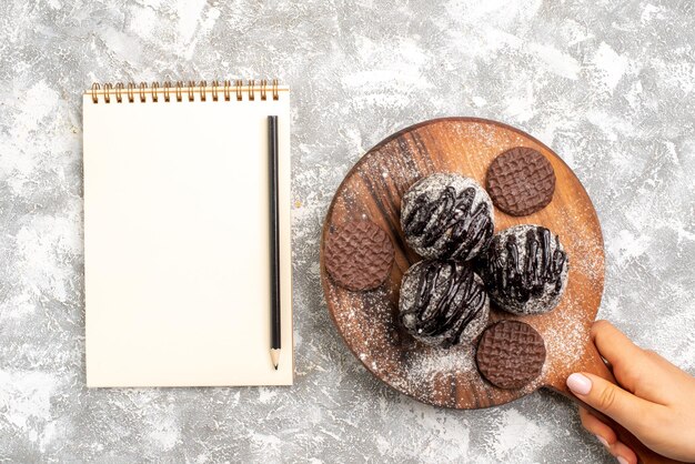 Vista dall'alto di deliziose torte di palline di cioccolato con i biscotti sulla superficie bianca