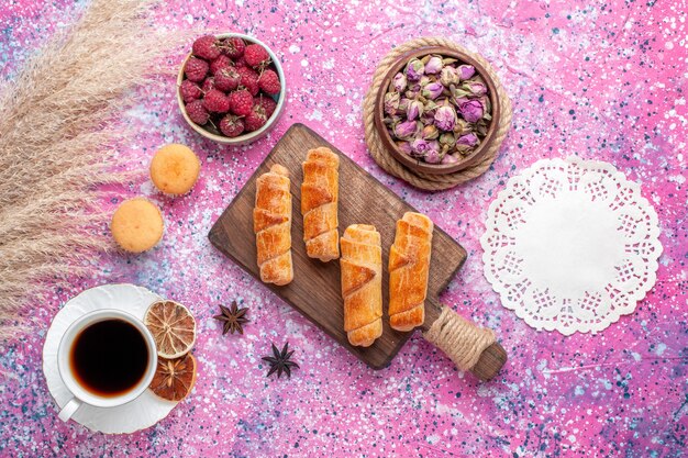 Vista dall'alto di deliziosi bagel con una tazza di tè sulla superficie rosa