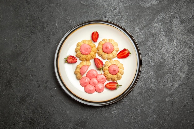 Vista dall'alto di deliziosi biscotti di zucchero con gelatina di fragole sulla superficie grigia