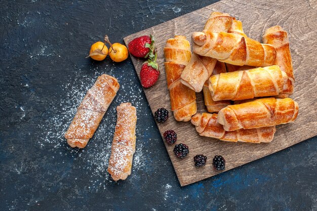 Vista dall'alto di deliziosi braccialetti dolci con ripieno delizioso al forno con frutta su dessert dolce zucchero scuro, cuocere torta biscotto