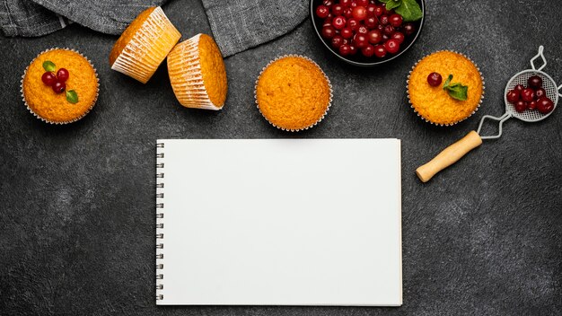 Vista dall'alto di deliziosi muffin con frutti di bosco e quaderni