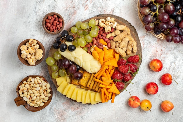 Vista dall'alto di deliziosi snack cips uva formaggio e noci sulla superficie bianca