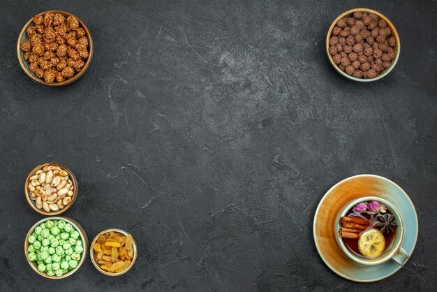 Vista dall'alto di diverse caramelle dolci con noci e tazza di tè su grigio