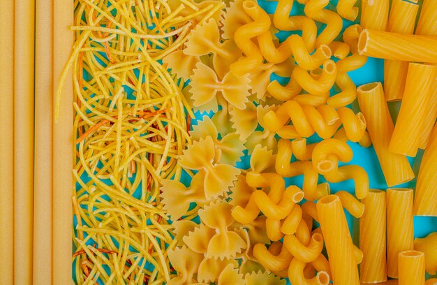 Vista dall'alto di diversi tipi di pasta sulla superficie blu