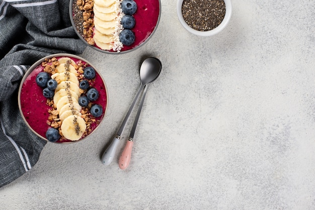 Vista dall'alto di dolci per la colazione in ciotole con frutta e copia spazio