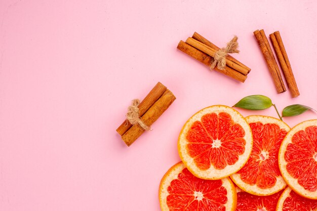 Vista dall'alto di fette di frutta succosa gustosi pompelmi con cannella sulla superficie rosa