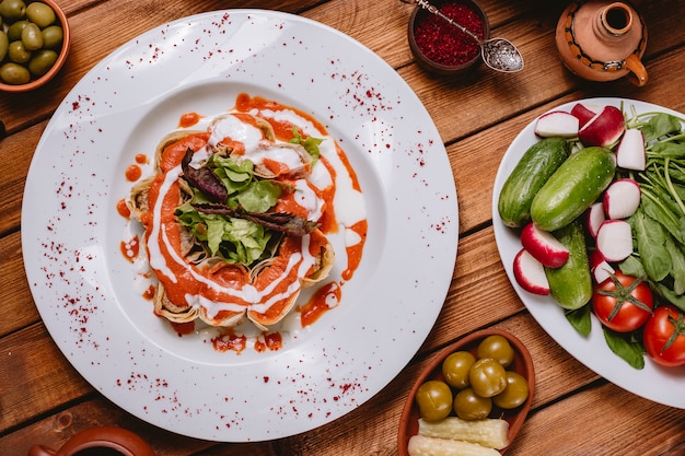 Vista dall'alto di fette di lula kebab avvolte in focaccia guarnite con salsa di pomodoro