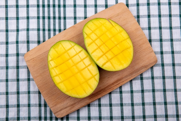 Vista dall'alto di fette di mango fresco delizioso esotico sul bordo della cucina in legno sulla tovaglia controllata